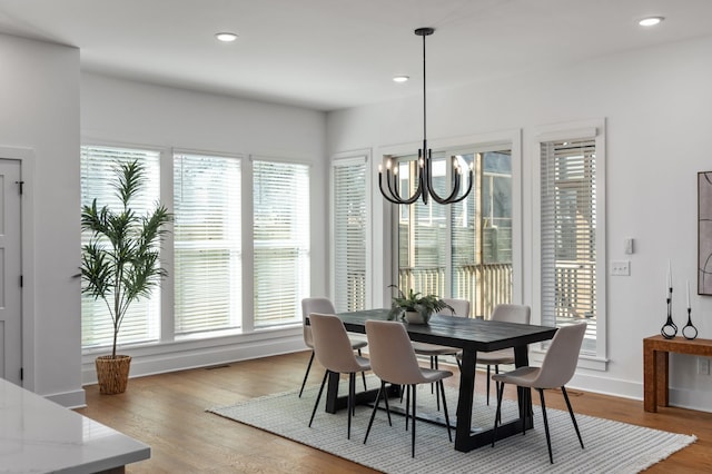 dining space with light wood-style floors, baseboards, an inviting chandelier, and recessed lighting