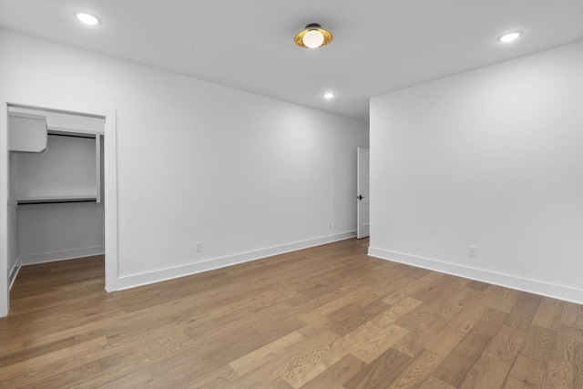 empty room with baseboards, light wood finished floors, and recessed lighting