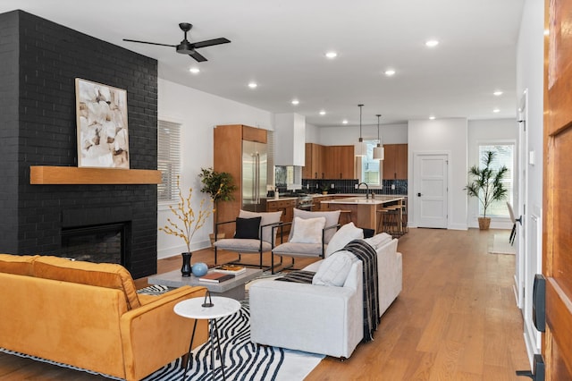 living room with plenty of natural light, light wood-type flooring, a fireplace, and recessed lighting