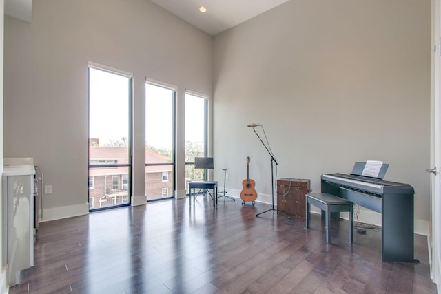 sitting room featuring dark wood finished floors, a towering ceiling, and baseboards