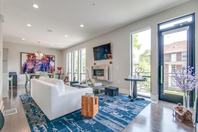 living area featuring baseboards, wood finished floors, an inviting chandelier, a fireplace, and recessed lighting