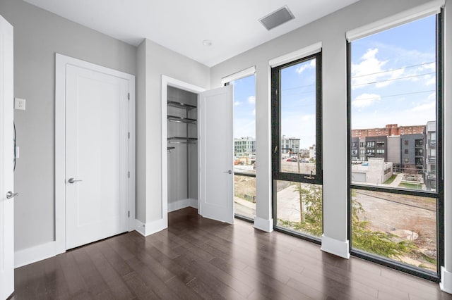 doorway to outside featuring a city view, dark wood finished floors, visible vents, and baseboards