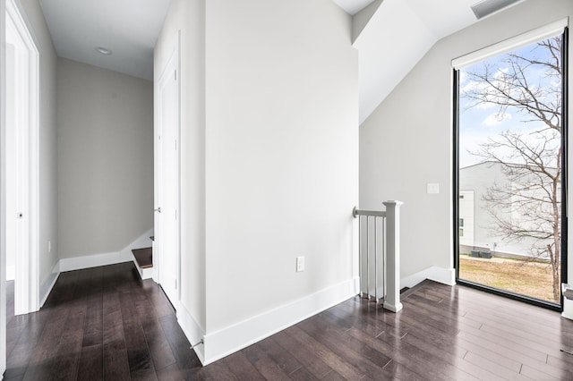 hall with wood finished floors, visible vents, and baseboards