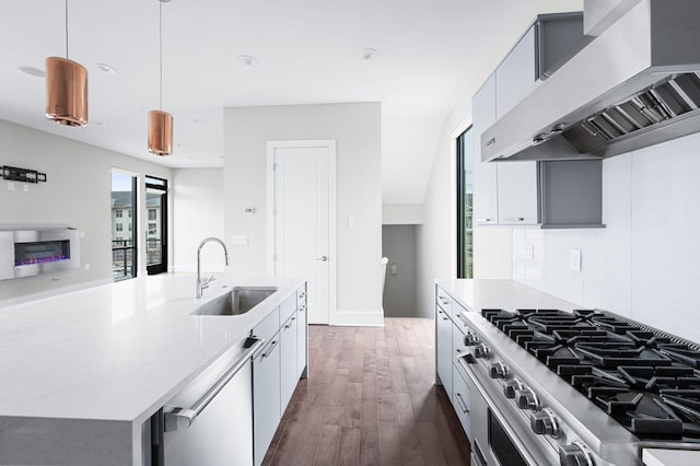 kitchen featuring dark wood-style flooring, a sink, high end stainless steel range, dishwasher, and wall chimney exhaust hood