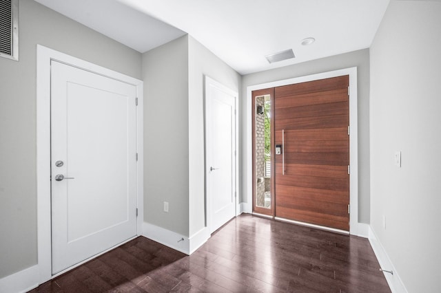 foyer entrance with visible vents, dark wood finished floors, and baseboards