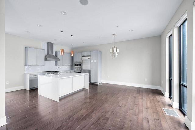 kitchen with visible vents, dark wood-style flooring, gray cabinets, light countertops, and wall chimney range hood