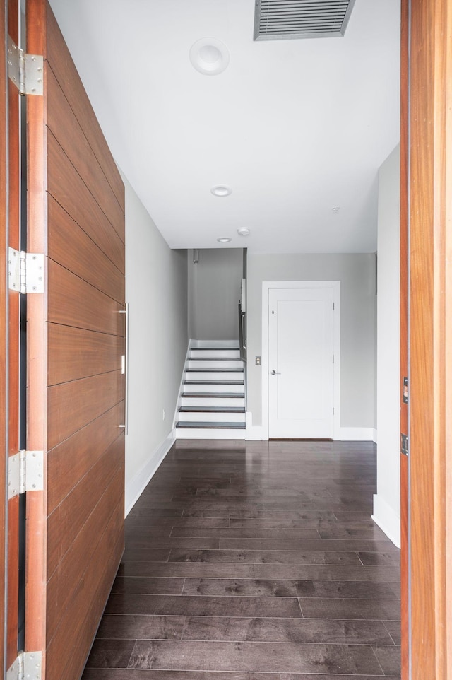 hall with visible vents, dark wood finished floors, baseboards, and stairs