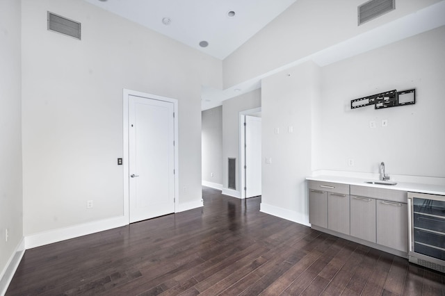 bar featuring beverage cooler, dark wood-type flooring, a sink, and visible vents