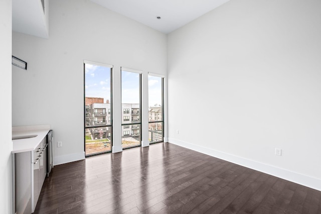 interior space with dark wood-style floors, a high ceiling, and baseboards