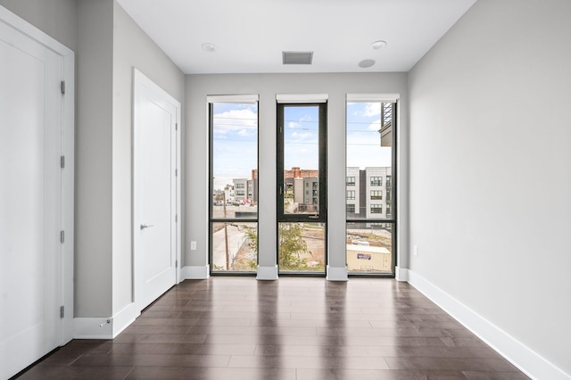 spare room with baseboards, visible vents, and dark wood finished floors