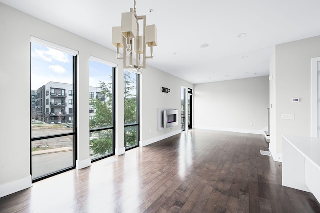 unfurnished living room with dark wood finished floors, heating unit, recessed lighting, a chandelier, and baseboards