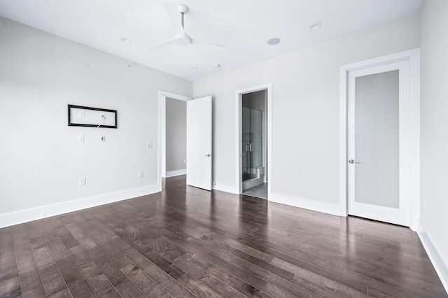 unfurnished bedroom featuring dark wood-style floors, connected bathroom, and baseboards