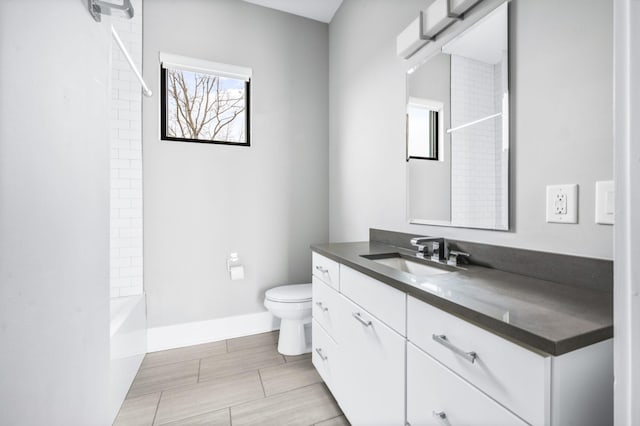 bathroom featuring baseboards, shower / bathing tub combination, vanity, and toilet