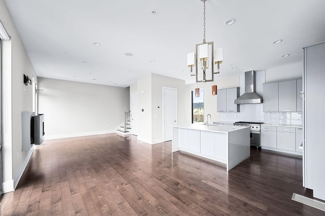 kitchen with dark wood finished floors, stainless steel range, open floor plan, modern cabinets, and wall chimney exhaust hood