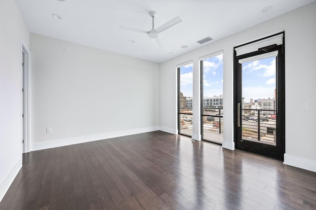 spare room with baseboards, visible vents, ceiling fan, dark wood-style flooring, and a view of city