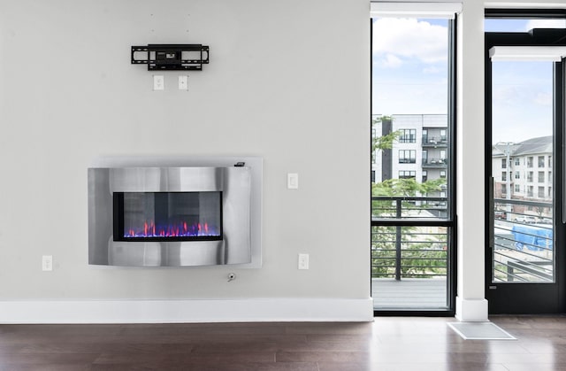 room details featuring baseboards, wood finished floors, and a glass covered fireplace