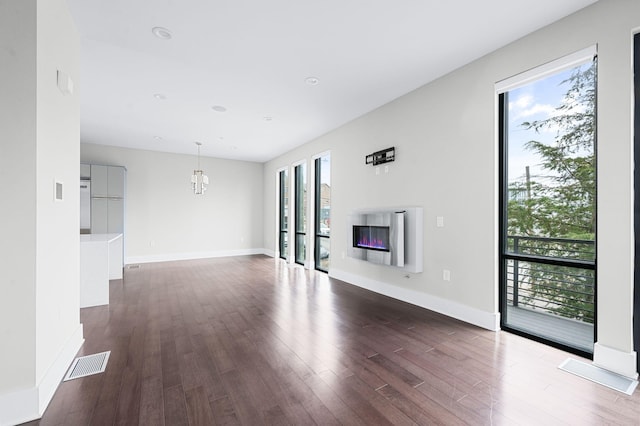 unfurnished living room with recessed lighting, dark wood-style flooring, visible vents, baseboards, and a glass covered fireplace