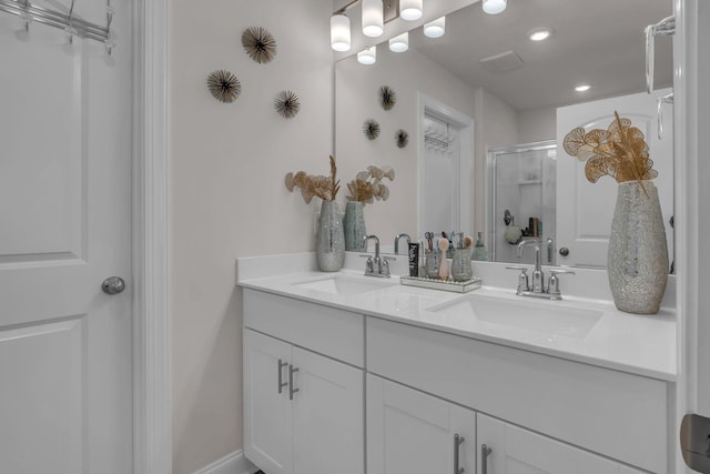 bathroom with double vanity, a stall shower, a sink, and recessed lighting