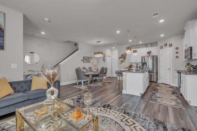 living room with baseboards, dark wood-style flooring, visible vents, and recessed lighting