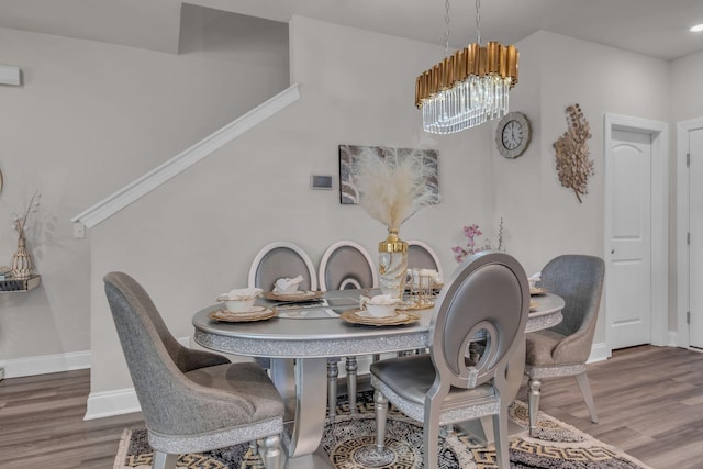 dining space featuring a chandelier, wood finished floors, and baseboards