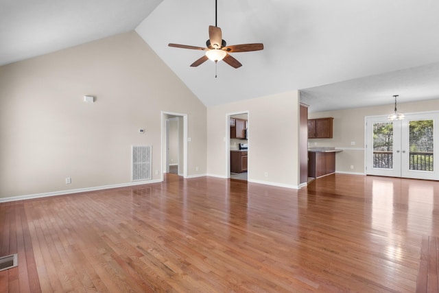 unfurnished living room featuring ceiling fan, high vaulted ceiling, visible vents, french doors, and light wood-type flooring