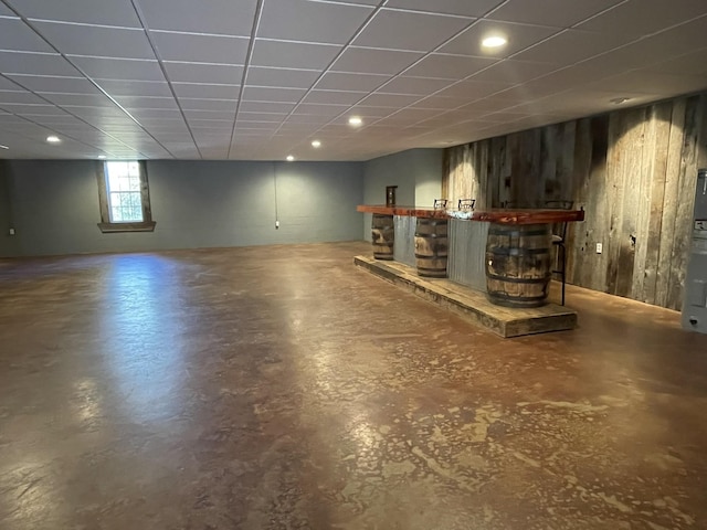 interior space featuring a bar, wooden walls, and a drop ceiling