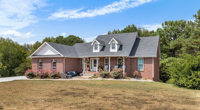 cape cod-style house with brick siding, a front lawn, and a shingled roof