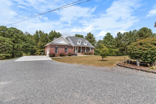 view of front of house featuring concrete driveway, brick siding, a front lawn, and covered porch