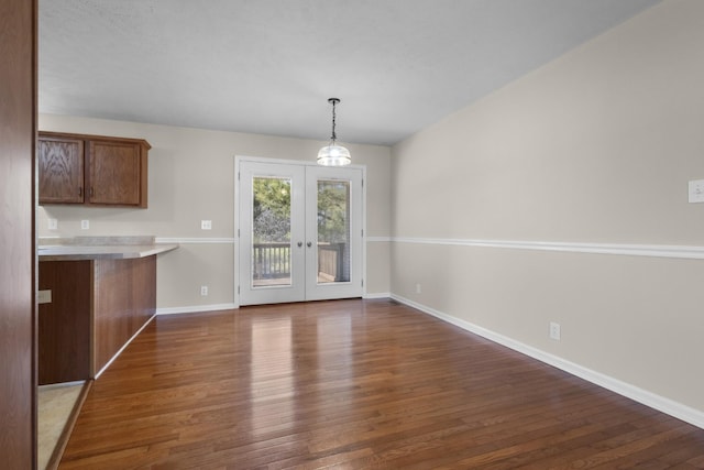 unfurnished dining area with dark wood-style floors, french doors, and baseboards