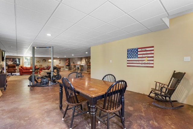 dining space with a paneled ceiling and finished concrete floors