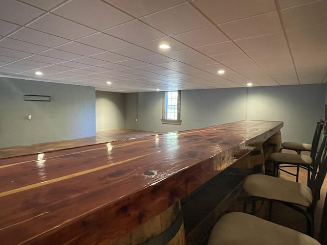 bar featuring concrete block wall, a drop ceiling, a dry bar, and recessed lighting