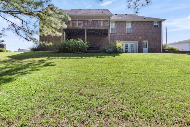 rear view of house featuring french doors, brick siding, a yard, and a deck