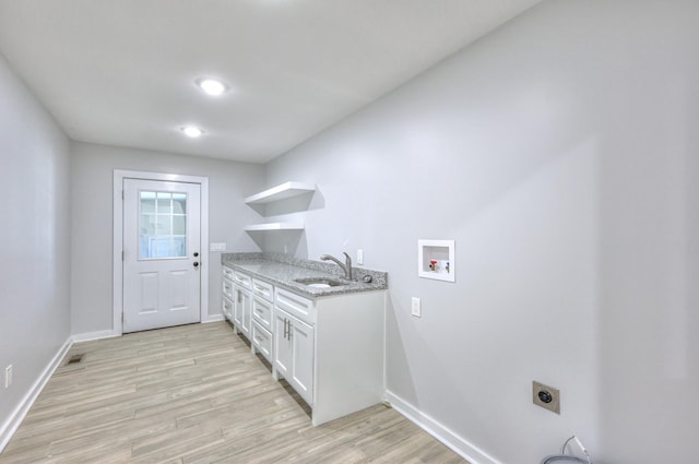 clothes washing area with hookup for a washing machine, hookup for an electric dryer, a sink, light wood-type flooring, and baseboards