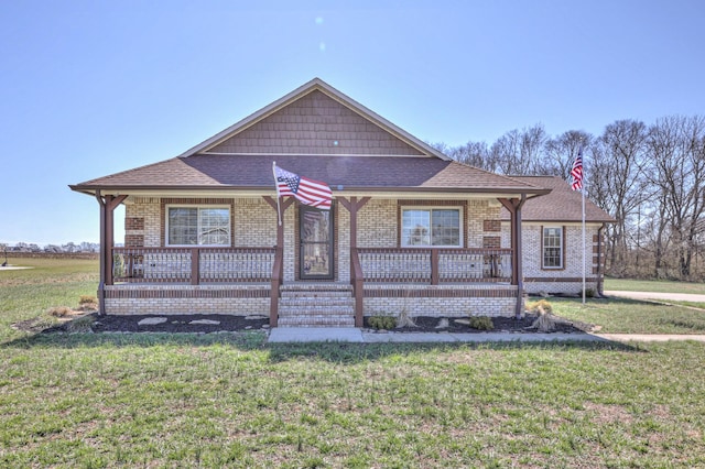 bungalow featuring a porch, a front yard, roof with shingles, and brick siding