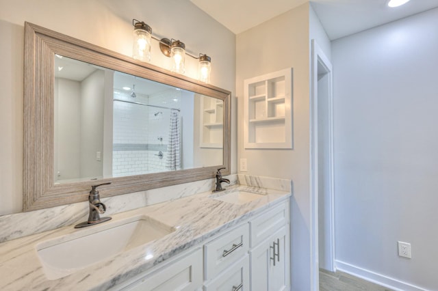 full bathroom featuring double vanity, a sink, and a shower with shower door