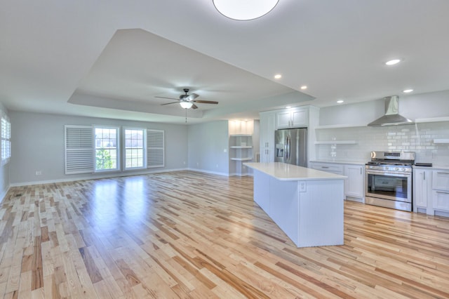 kitchen featuring extractor fan, stainless steel appliances, light wood-style floors, open shelves, and a tray ceiling