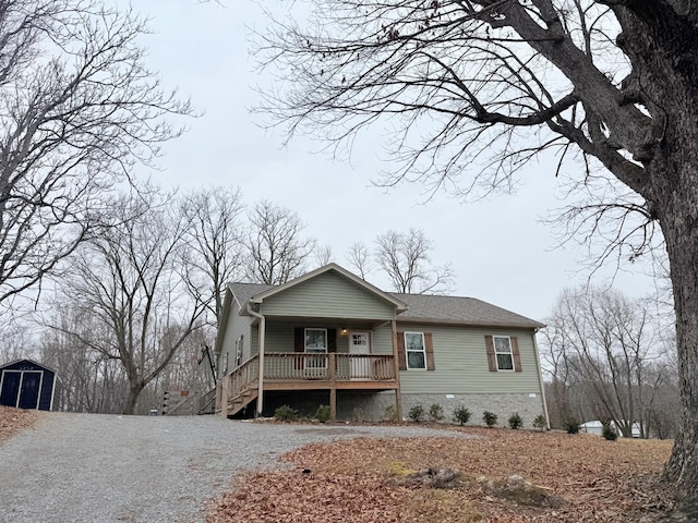 view of front facade featuring gravel driveway, a porch, a shingled roof, crawl space, and an outdoor structure