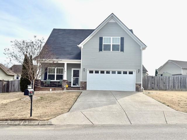 view of front facade with a porch, concrete driveway, fence, and a garage