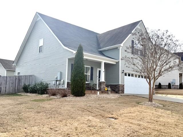 view of front of house with a front lawn, fence, a porch, a garage, and driveway