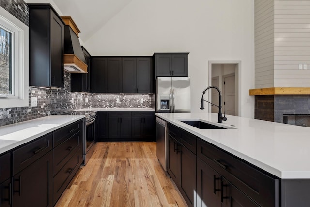 kitchen with stainless steel appliances, a sink, light countertops, custom exhaust hood, and tasteful backsplash