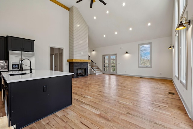 kitchen with light countertops, visible vents, a tiled fireplace, dark cabinets, and stainless steel fridge with ice dispenser