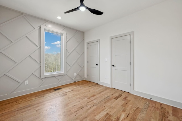 unfurnished bedroom with light wood finished floors, visible vents, ceiling fan, a decorative wall, and recessed lighting