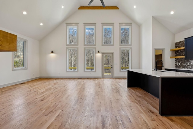 kitchen featuring open shelves, light wood finished floors, light countertops, and a sink