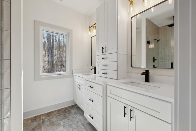 full bathroom featuring double vanity, a stall shower, a sink, and baseboards