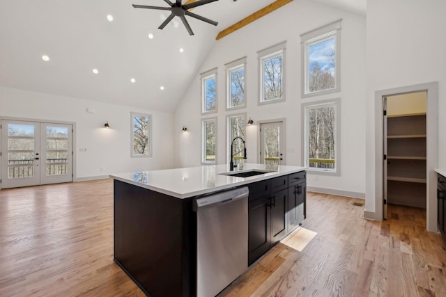 kitchen with light countertops, a sink, light wood finished floors, and stainless steel dishwasher