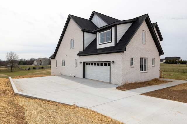 view of home's exterior with concrete driveway, brick siding, an attached garage, and fence