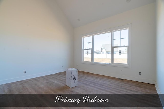 unfurnished room with baseboards, vaulted ceiling, and wood finished floors