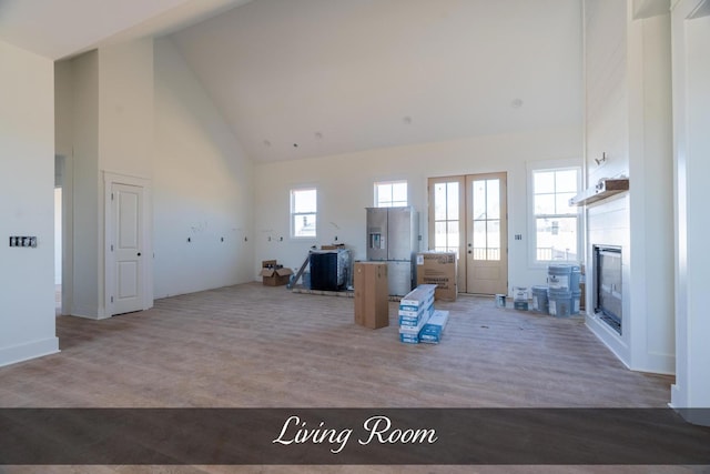 unfurnished living room featuring high vaulted ceiling, wood finished floors, and a glass covered fireplace