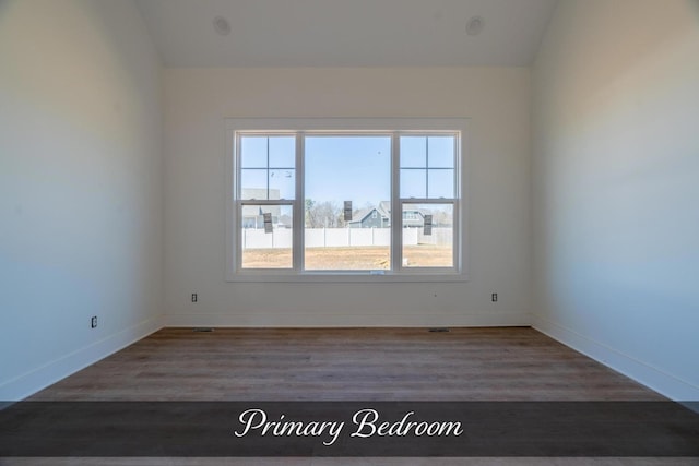 spare room with lofted ceiling, baseboards, and wood finished floors