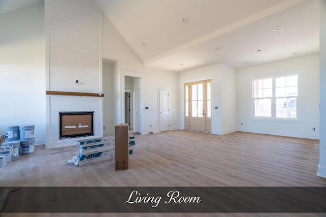 living area featuring a large fireplace, high vaulted ceiling, wood finished floors, and baseboards